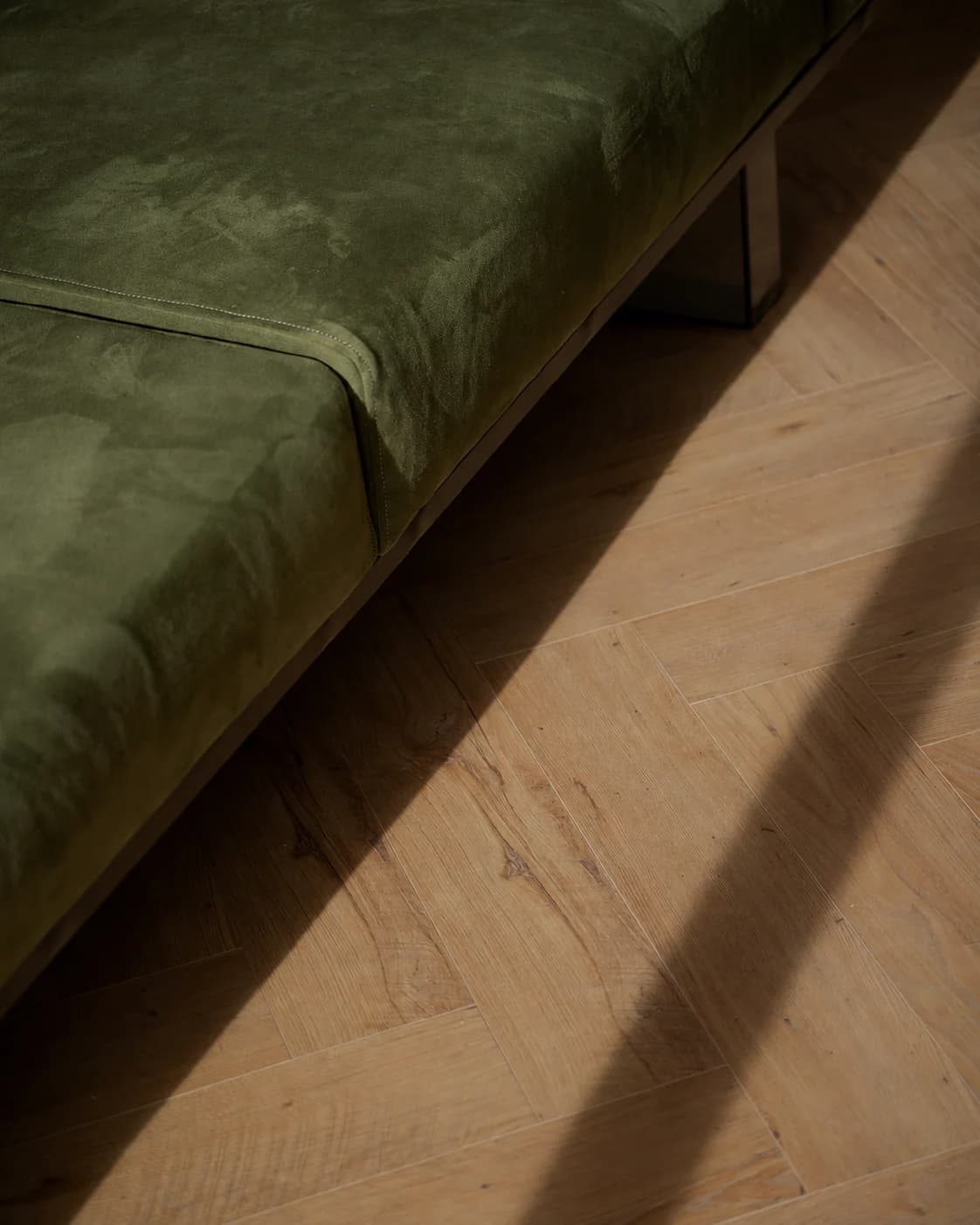 Green velvet sofa on a herringbone oak floor